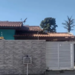 Foto de casa à venda em Rio das Ostras, na Extensão do Bosque. Imóvel da cor azul, com portão branco automático, muro com revestimento na cor cinza, com cerca elétrica e segurança.
