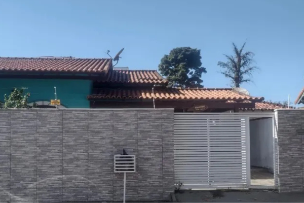 Foto de casa à venda em Rio das Ostras, na Extensão do Bosque. Imóvel da cor azul, com portão branco automático, muro com revestimento na cor cinza, com cerca elétrica e segurança.